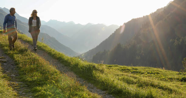 istock Mature couple hike through grassy meadow, chatting 1329571033