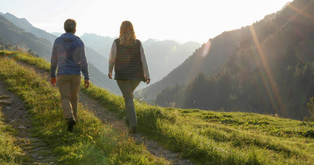 mature couple hike through grassy meadow, chatting - 5515 imagens e fotografias de stock