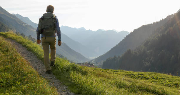 istock Man hikes through grassy meadow in the morning 1329571090