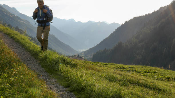 istock Man hikes through grassy meadow in the morning 1329571110