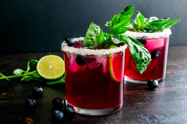 Roasted Blueberry Basil Margaritas Garnished with Fresh Basil and Blueberries Margarita cocktails made with tequila, basil, and blueberries and rimmed with a salt and sugar mixture lime basil plant stock pictures, royalty-free photos & images