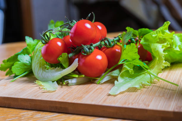 Fresh cherry tomatoes with green salad and garlic on a cutting board. Healthy food concept. Vegetarianism.