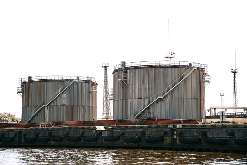 Industrial zone with storage tanks in the cargo port. large fuel loading terminal at the pier harbor, white sky background