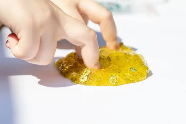 Photo of child playing with shiny slime, hands close up