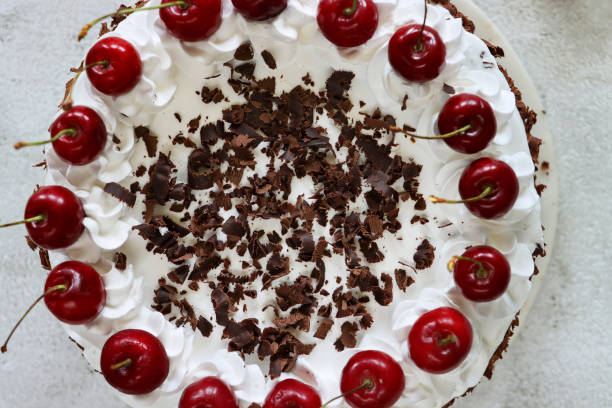 istock Close-up image of Black Forest gateau with piped whipped cream rosettes topped with morello cherries, luxury chocolate cake frosted with whipped cream and covered with chocolate shavings, marble effect background, elevated view 1329585680