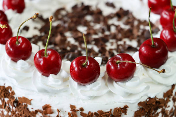 istock Full frame image of Black Forest gateau with piped whipped cream rosettes topped with morello cherries, luxury chocolate cake frosted with whipped cream and covered with chocolate shavings, elevated view, focus on foreground 1329585764
