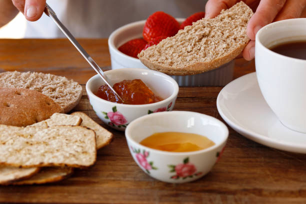 Wholemeal bread with jam for breakfast, woman's hands prepating food, healthy eating concept