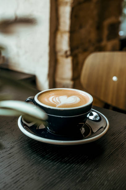 istock Cappuccino coffee cup on black wooden table lights and shadows 1329594673