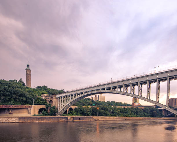 Wide horizontal view of the historic High Bridge spanning the Harlem River and Highbridge Water Tower is the distance. Bronx, NY - USA - July 17, 2021: Wide horizontal view of the historic High Bridge spanning the Harlem River and Highbridge Water Tower is the distance. bridge crossing cloud built structure stock pictures, royalty-free photos & images