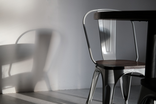 Modern loft grey color metal chair at coffee shop. Creative interior detail photo in lights and shadows. Minimalist concept, lifestyle, close up