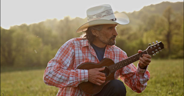 istock Cowboy in nature playing the guitar at sunset. Springtime staycation. 1329596792