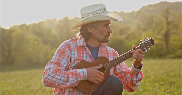 istock Cowboy in nature playing the guitar at sunset. Springtime staycation. 1329596795