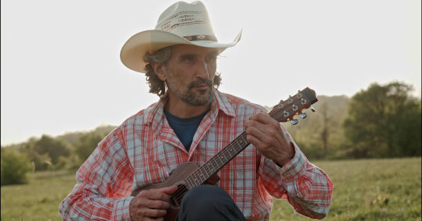 istock Cowboy in nature playing the guitar at sunset. Springtime staycation. 1329596799