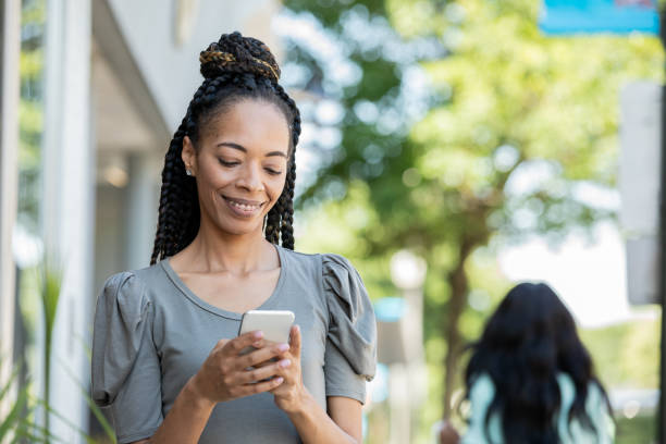 istock Woman uses smart phone to check social media while walking on sidewalk 1329596972