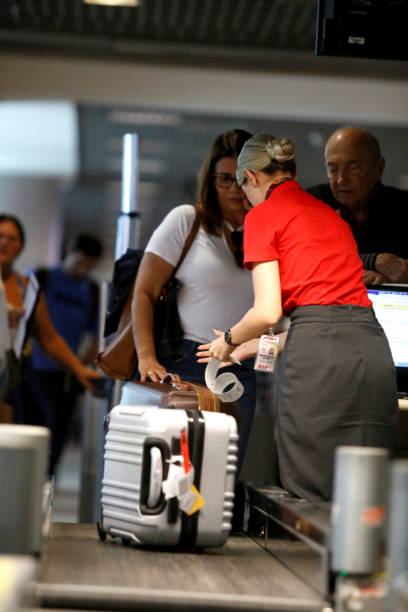 airline check-in service salvador, bahia, brazil - july 27, 2018: an airline attendant weighs a suitcase on a conveyor belt at check-in at the airport in the city of Salvador. priority baggage tag stock pictures, royalty-free photos & images
