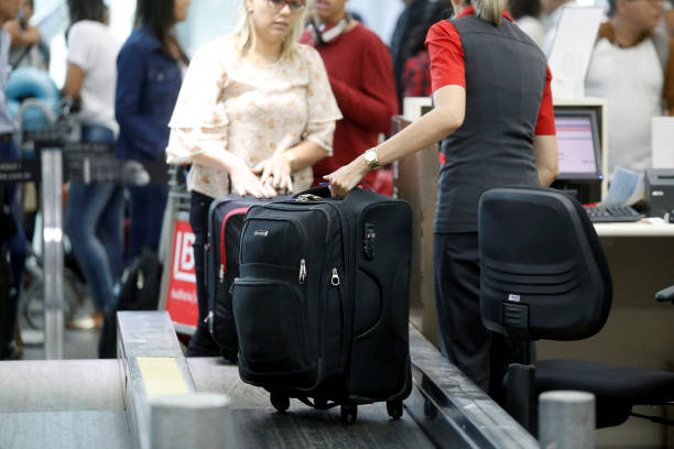 airline check-in service salvador, bahia, brazil - july 27, 2018: an airline attendant weighs a suitcase on a conveyor belt at check-in at the airport in the city of Salvador. priority baggage tag stock pictures, royalty-free photos & images