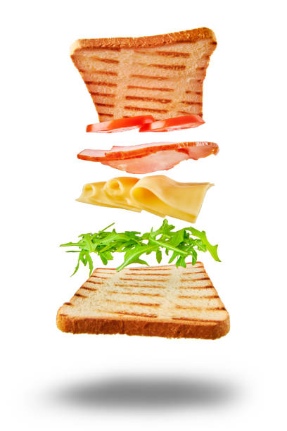 Flying sandwich with ingredients on wite background Ingredients for sandwich flying over table on white background. Creative food concept arugula falling stock pictures, royalty-free photos & images