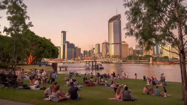 Picnics on Riverside Green in South Bank, a recreational area in Brisbane, Australia, likely host of the 2032 Olympic Games. South Bank looks across the Brisbane River to the city skyline.