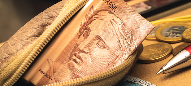 Real - BRL, dinero de Brasil. Un billete de dinero brasileño dentro de un monedero. En la composición hay monedas y un bolígrafo en un sobre de papel marrón. Foto de primer plano. photo