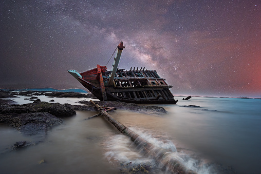 Boat crashes in the sea and milky way. Climate change.
