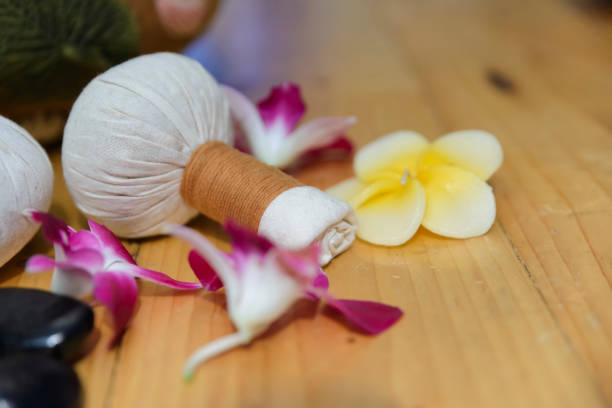 spa-massage auf holztisch, kompressenkugel plumeria und orchideenblüten. - herbal compress balls stock-fotos und bilder