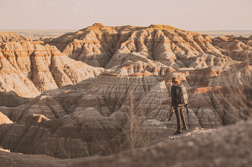 Male photographer standing in front of vast canyon badland in golden light