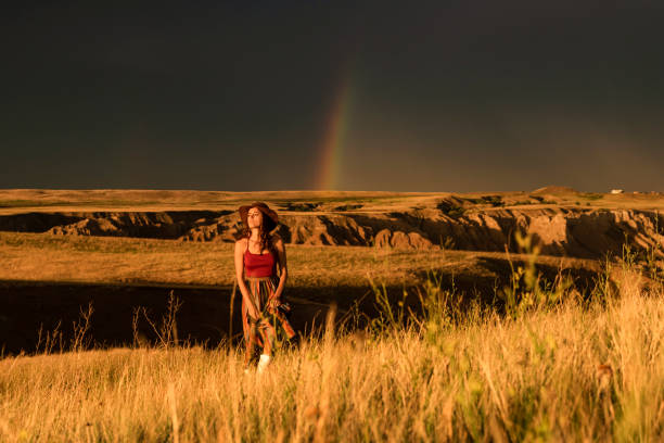 istock Woman walking through golden fields under rainbow sky at sunset 1329614472