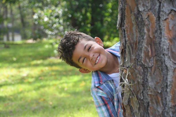 istock Smiling boy peeks out from behind the tree. 1329614478