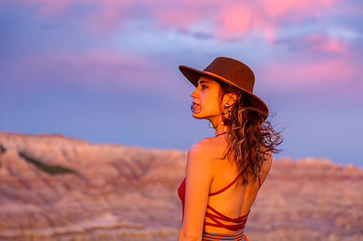 Close up portrait of beautiful woman overlooking a desert canyon sunset under pink and violet sky