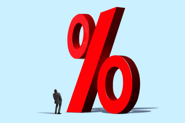 A man looks up at a large red percentage sign isolated on blue background