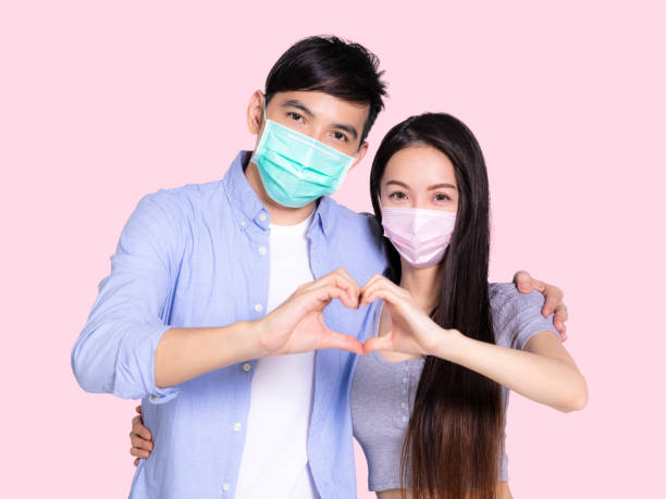 istock Young couple wearing with mask and making hand heart gesture 1329620775