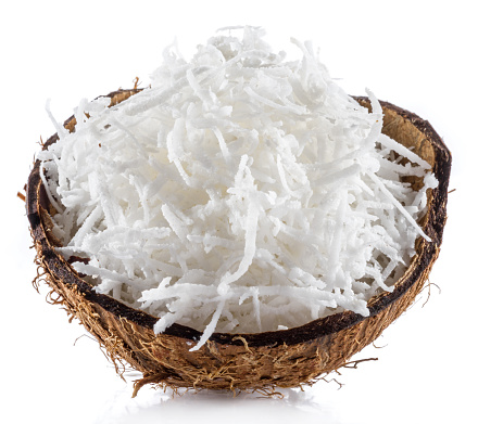 Shredded coconut flakes in the piece of coconut shell isolated on white background. Close-up.