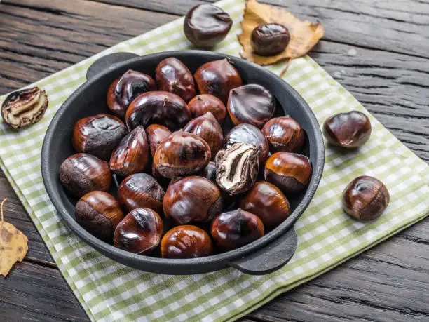 Photo of Roasted edible chestnut fruits in the pan. Top view.