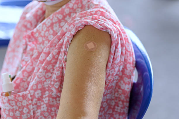 close-up arm of thai asian old woman with a plaster attached on upper arm after vaccination against covid-19 for build immunity on body, preventing infectious disease outbreaks through vaccination - immune defence fotos imagens e fotografias de stock