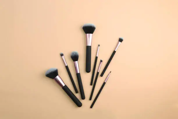 Photo of A set of makeup brushes on a beige background. Brushes for applying cosmetics. Cosmetology, make-up. Copy space