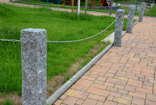 stone fence post at the monument to the fallen in the war. connected to another metal chain, protects against entering the lawn. cemetery scattering meadow of ashes - driveway brick paving stone interlocked imagens e fotografias de stock