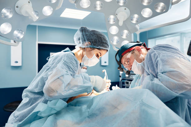 Surgeons in a light operating room perform plastic surgery, a team of male and female doctors perform reconstructive surgery stock photo