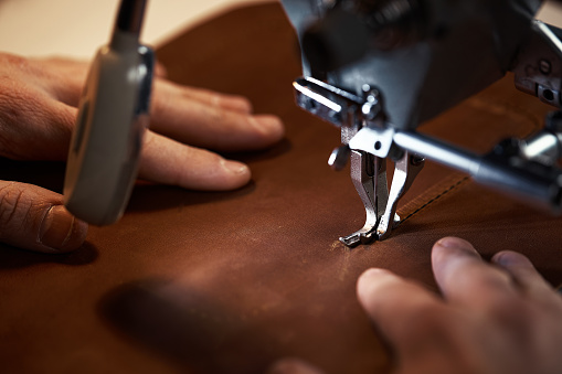 Leatherworker workflow. A tanner or skinner sews leather on a special sewing machine. A worker sews on a sewing machine, first-person view