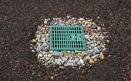 roof gutter covered with a square plastic green grid. green roofs covered with substrate. the area around the drain is mulched with stone mulch from pebbles, substrate