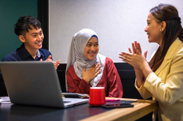 istock Asian business people clapping hands while meeting for success in modern office 1329634577