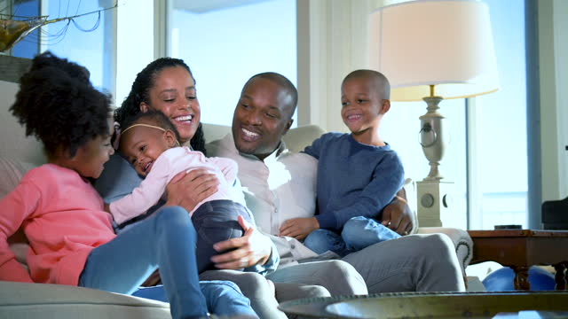 African-American family, three children, gather on sofa