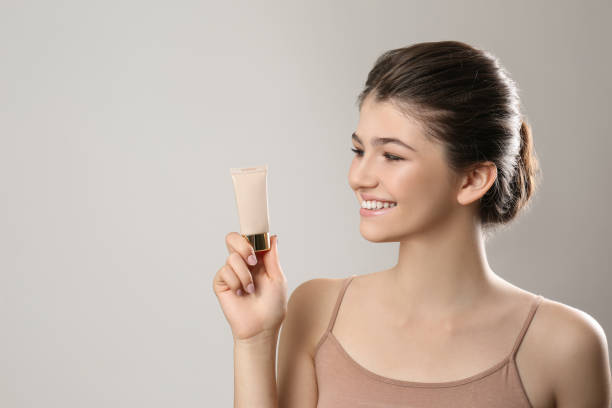 beautiful girl with tube of foundation on light grey background - adolescence teenagers only teenager making a face imagens e fotografias de stock