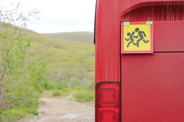 ein roter bus mit kindern. . transport von kindern. ein warnkinderschild befindet sich auf der rückseite des busses. - bus coach bus travel red stock-fotos und bilder