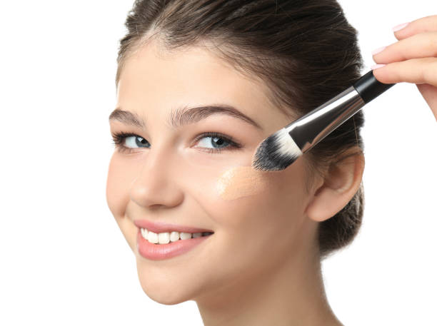 beautiful girl applying foundation with brush on white background. face contouring - adolescence teenagers only teenager making a face imagens e fotografias de stock