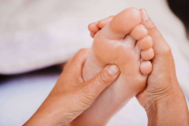 Close up of foot reflexology showing female hands on a acupressure point on the plantar surface Close up of foot reflexology showing female hands on the acupressure on the plantar surface. Alternative treatment. Color editing with slightly grain. Part of a series. pressure point photos stock pictures, royalty-free photos & images