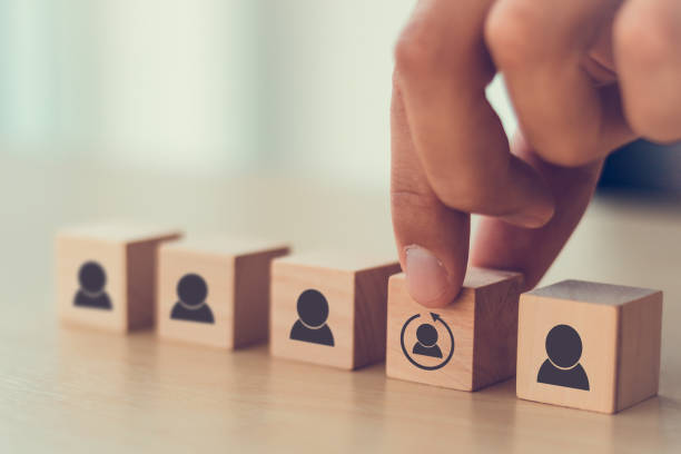 Re-skill concept to training employees on an entirely new set of skills for business growth and digital transformation. Man holds wood cube with re-skill icon on many staff icon symbol; Copy space. concepto de recapatención para capacitar a los empleados en un conjunto completamente nuevo de habilidades para el crecimiento empresarial y la transformación digital. el hombre sostiene el cubo de madera con el icono de la re-habilidad en el símbolo de