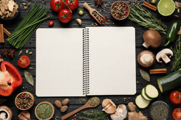 istock Open recipe book and different ingredients on black wooden table, flat lay. Space for text 1329646983