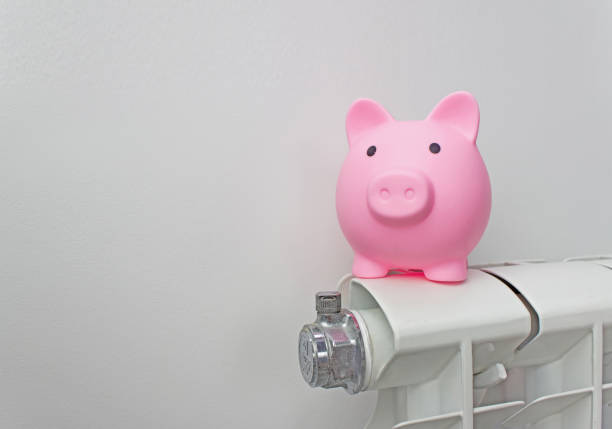istock Piggy bank on radiator. Energy saving. Saving heating in winter. Expensive heating costs concept. 1329648517