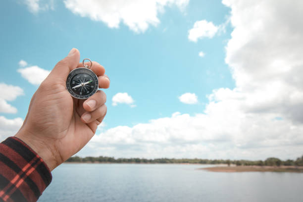 istock Male hands holding a compass on the sky background 1329651234