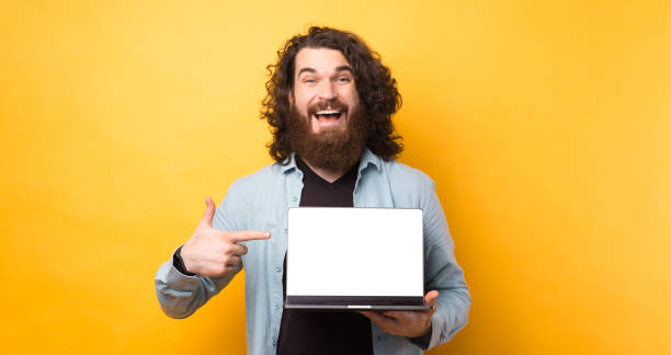 istock Excited happy bearded man pointing finger at screen laptop computer over yellow background 1329652630